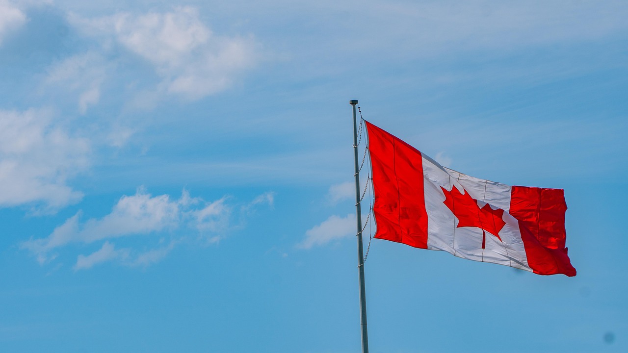 Canadian flag flying under a blue sky